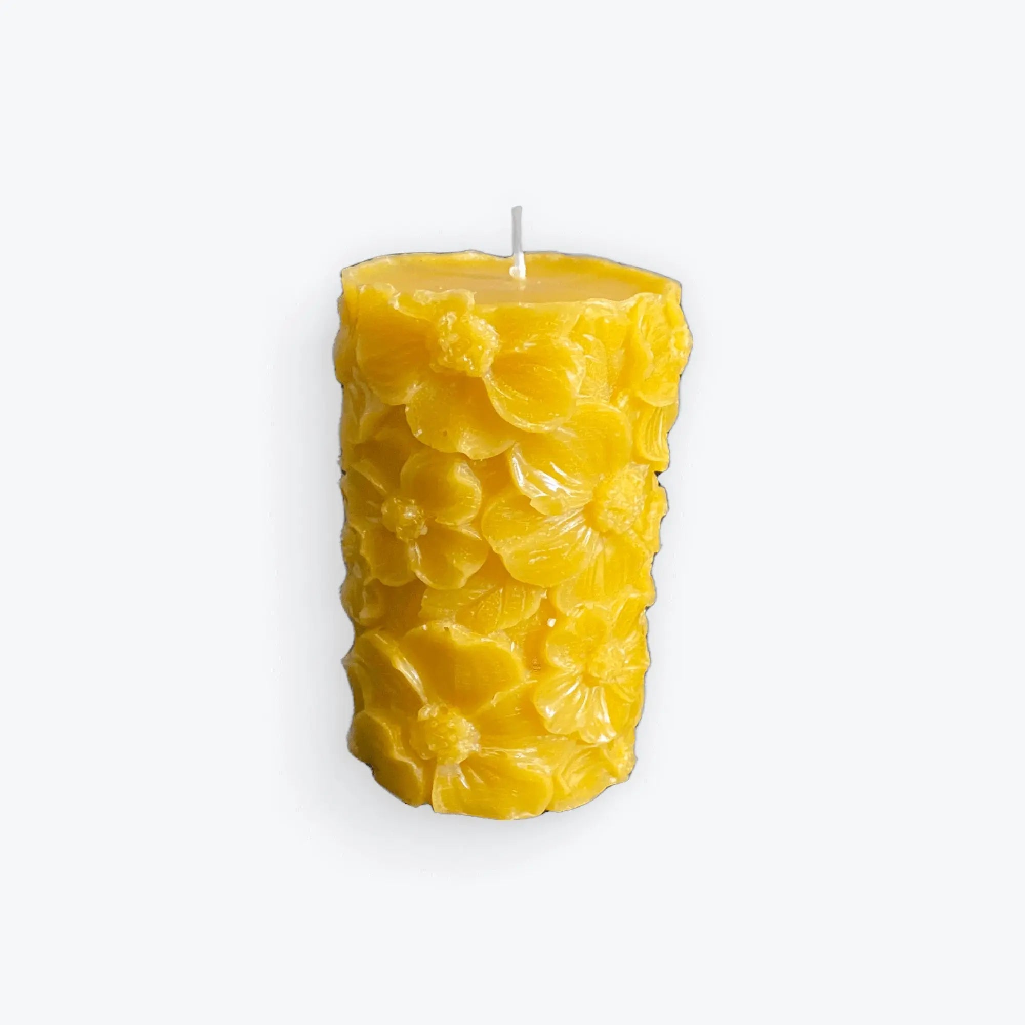 Yellow beeswax candle with intricate floral designs, handmade and natural British wax