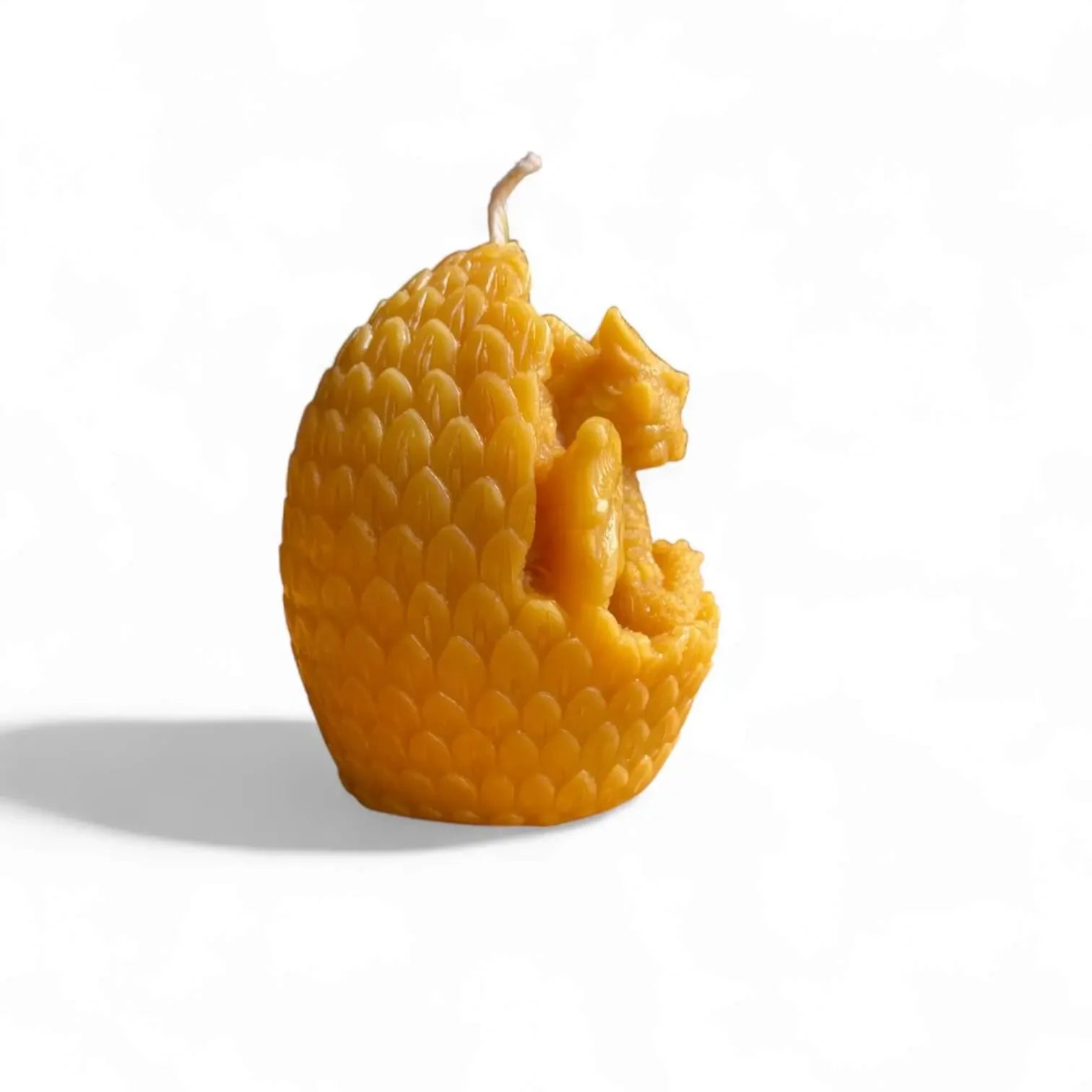 Yellow beeswax candle shaped like a dragon egg with a dragon emerging from inside