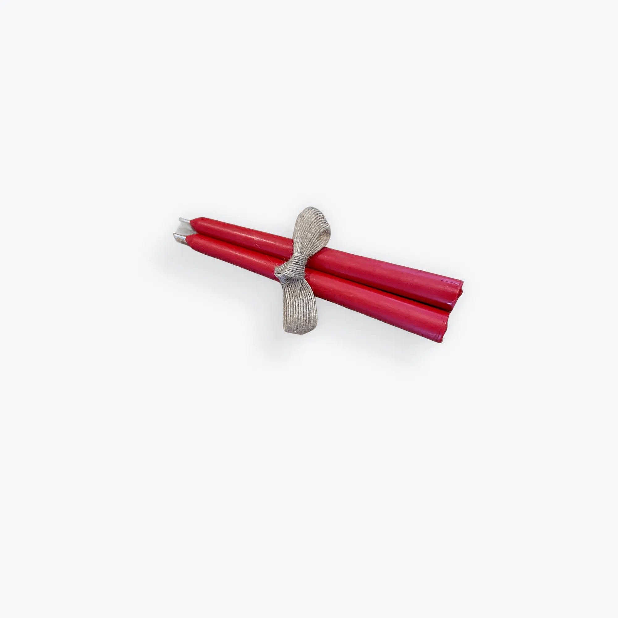 Pair of elegant red taper beeswax candles tied with a silver textured ribbon on white background