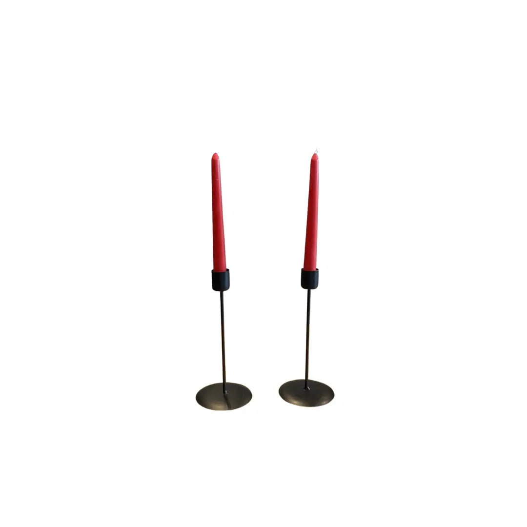 Pair of red beeswax taper dinner candles in minimalist black metal holders on white background