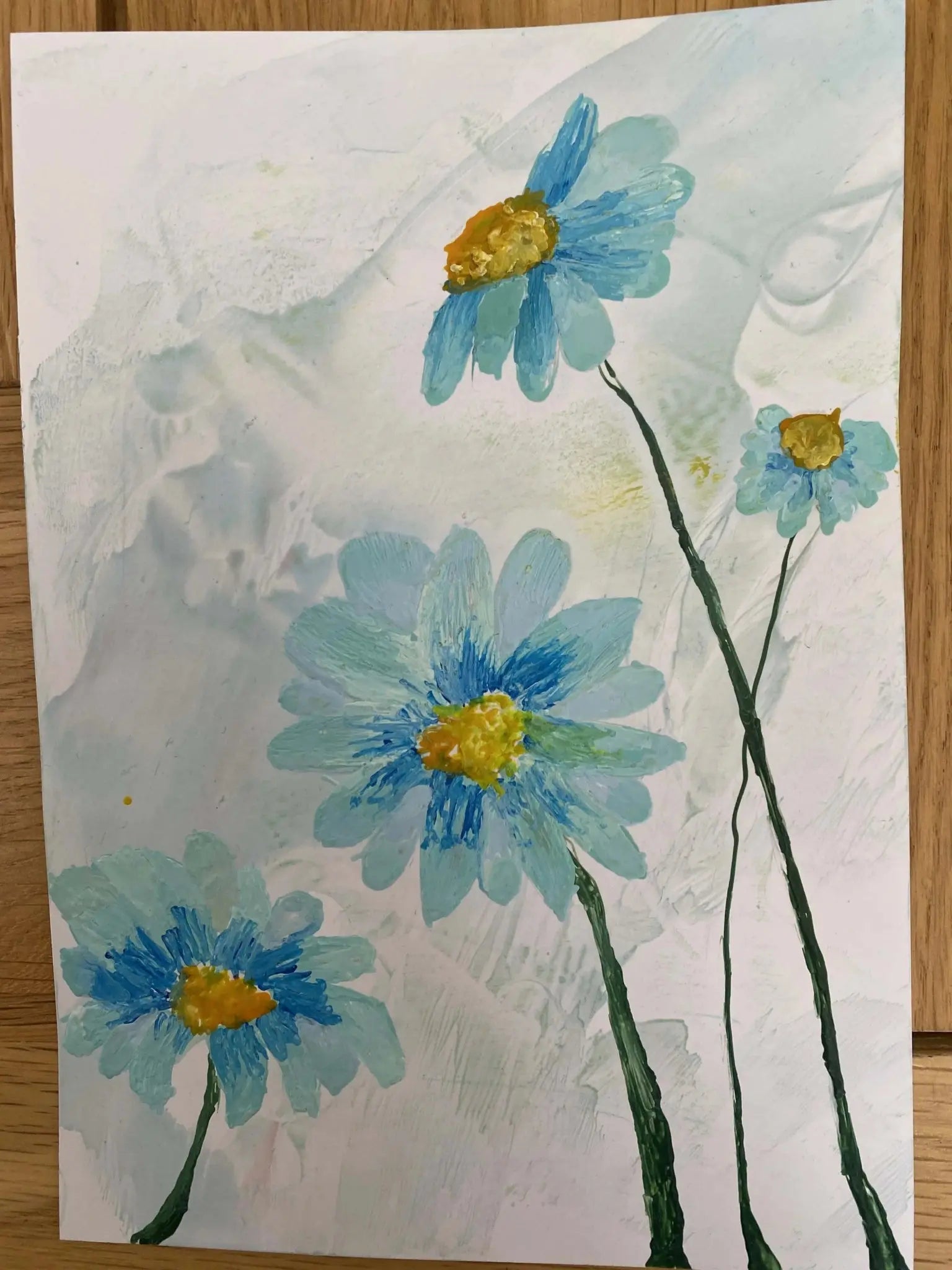 Encaustic artwork featuring four blue daisies with yellow centers on textured white background