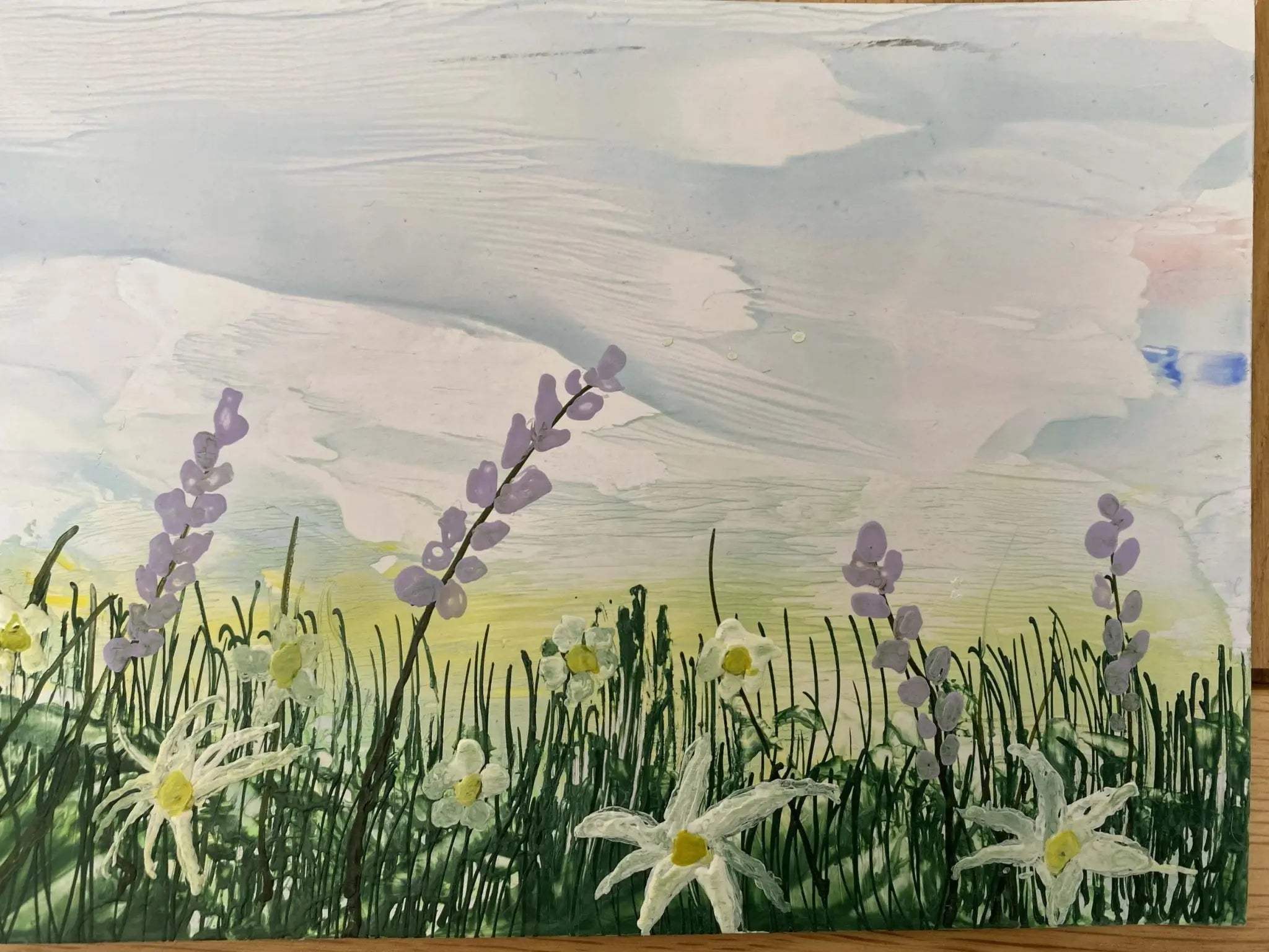 Encaustic artwork of wildflower field with white daisies and purple flowers on green grass under a cloudy sky