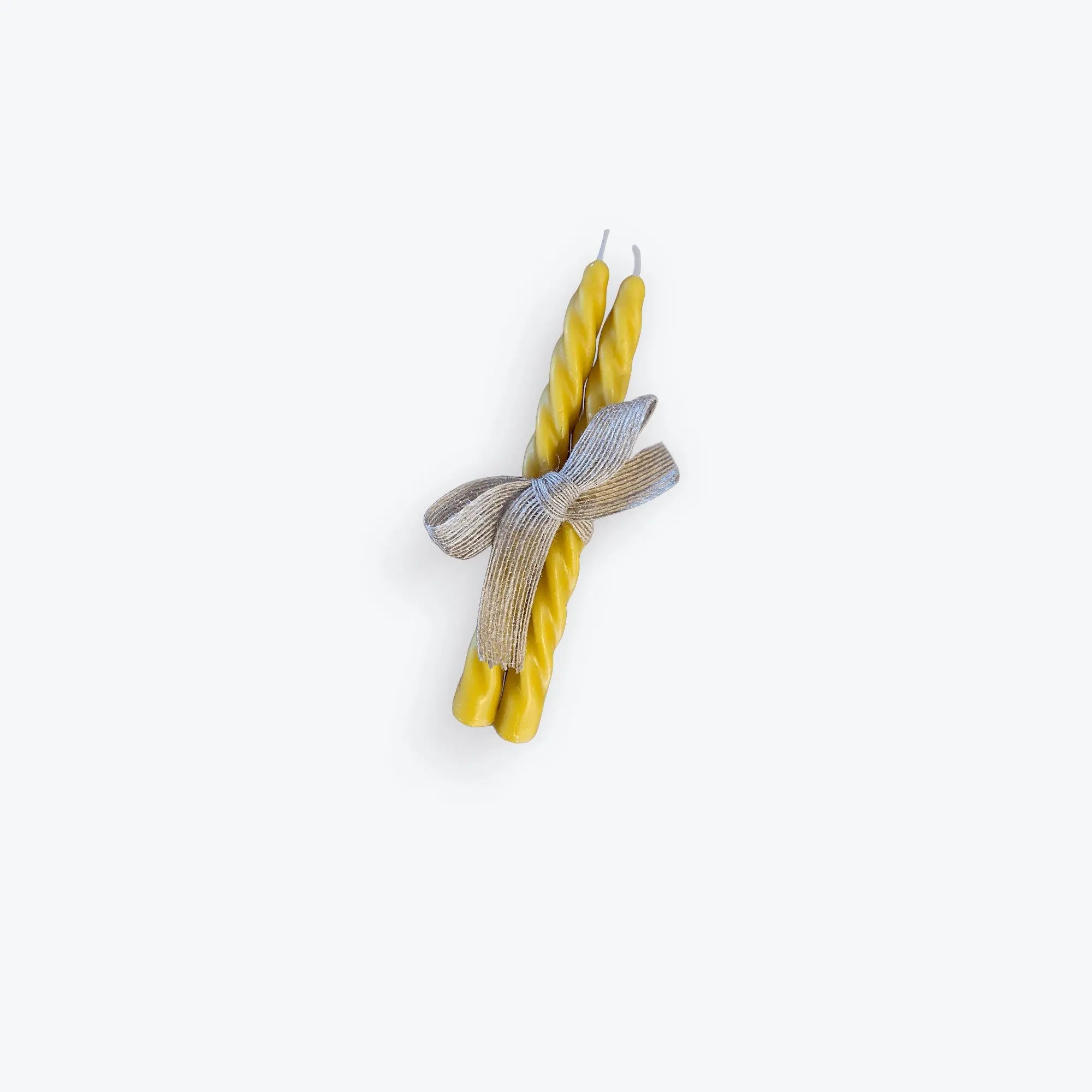 Pair of yellow spiral taper beeswax candles tied with a natural beige bow on white background